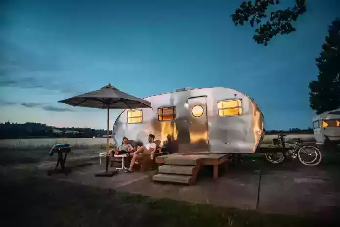 man and woman sitting in front of RV trailer